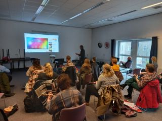Nascholing muziekmethodes - Iemand geeft een presentatie en een volle klas met leraren kijkt ernaar.